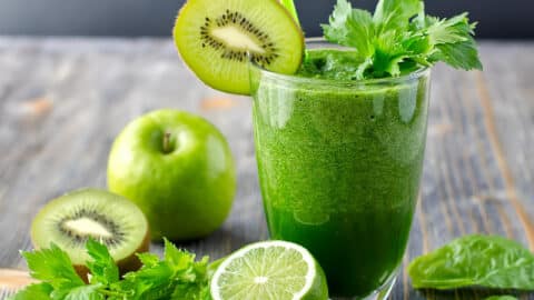 Świeżo zblendowane zielone smoothie z jabłka, kiwi i szpinaku w szklance, obok świeże owoce i liście szpinaku na stole, przygotowane na szybkie śniadanie.